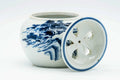 Blue-and-white Kutani-yaki cha-koboshi water bowl with its pierced strainer lid leaning against it, three-quarter view.