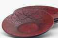 Closeup of a red lacquer saucer showing the carved flower motif and scaled texture.