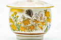 Close-up of the cup body detailing the gold and orange floral motif, lid on.