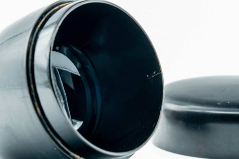 Weathered black-lacquer matcha tea caddy, angled view with lid off, showing the interior and the underside of the lid