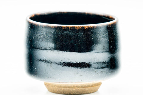 Close-up three-quarter view of a single black cup showing the glossy glaze with a lighter speckled rim.