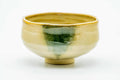 Akahada-yaki matcha chawan in cream-beige glaze with a green drip, three-quarter view