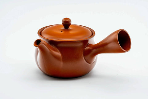 Three-quarter view of the round red kyusu with the lid on.