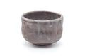 Hand-formed Mino-yaki matcha bowl (chawan) with mottled brown and milky-beige glaze, three-quarter view showing the irregular hand-shaped rim