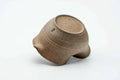 The ash-glazed katakuchi resting on its side, showing the pale exterior and base.