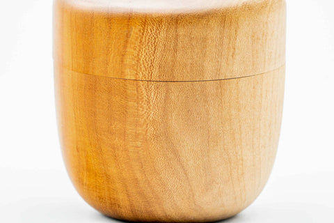 Close-up of the closed wooden canister filling the frame to show the warm grain.