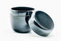 Glossy black-urushi matcha tea caddy (natsume) with lid removed and lying flat beside the upright body, three-quarter view