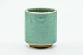 Tall cylindrical yunomi with a green celadon glaze full of fine crazing, front view.
