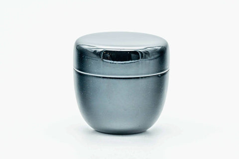 Small black lacquer natsume caddy with lid on, shown at a three-quarter angle.