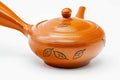 Closeup of the engraved leaves motif on the body of the red shudei Tokoname kyusu beside the lid