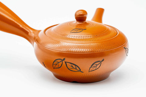 Closeup of the engraved leaves motif on the body of the red shudei Tokoname kyusu beside the lid