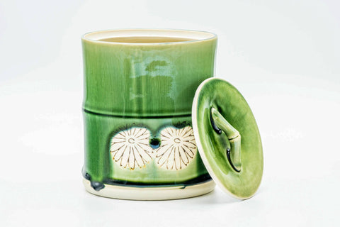Mizusashi with its green lid lifted and set to one side, showing the rim.