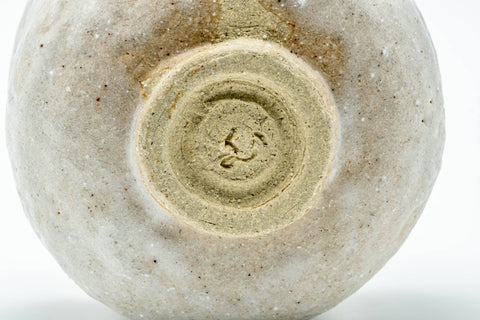 Close view of the foot and lower body showing the carved foot ring and milky glaze.