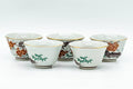 The row of teacups from another angle, showing the painted decoration and rims.