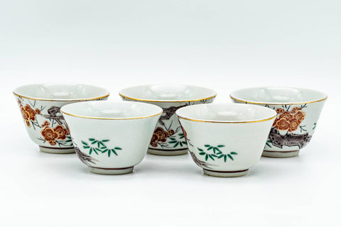 The row of teacups from another angle, showing the painted decoration and rims.