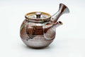 Brown-and-cream drip-glazed side-handle kyusu with a flared spout, lid on, three-quarter view.