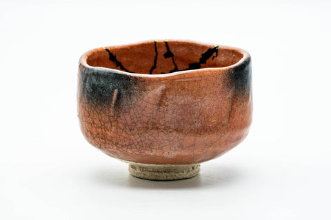 Front view of the raku chawan showing gold-mended cracks and mottled orange-and-black glaze.
