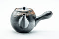 Three-quarter front view of a matte black kyusu teapot with brown drip-glaze accents, lid on, side handle at right and spout at left.