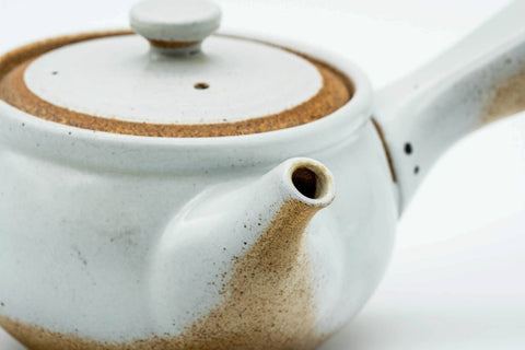 Side view showing the spout and the contrast between the white glaze and brown clay.