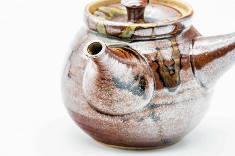 Three-quarter view showing the drip glaze and flared spout, lid on.