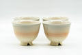 Set of four Hagi-yaki yunomi teacups arranged together, pale beige and peach glaze with soft striations