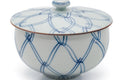 Close-up of the lidded cup showing the blue lattice design and brown-edged rim.