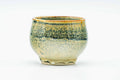 Side view of the green-and-yellow drip-glazed cup.