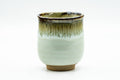 Front/side view showing the streaked drip glaze over the pale body.