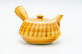 Side profile of the yellow ribbed teapot with the spout pointing to the left