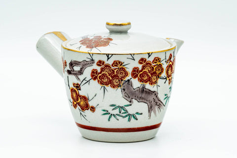 Front view of the white Kutani-yaki kyusu teapot with red-and-green floral painting and gold accents.