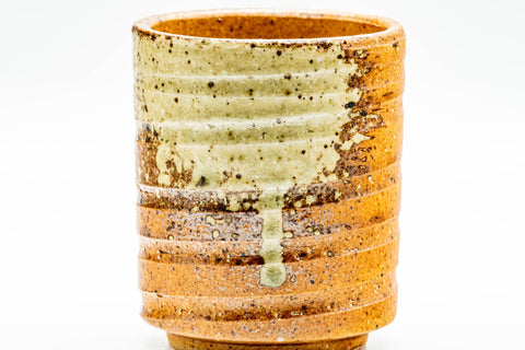 Three-quarter front view of the Shigaraki yunomi highlighting green ash-glaze runs over the spiraled orange clay