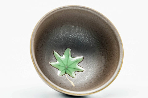 Close-up of a cup's interior, showing the green leaf decoration.