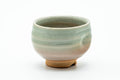 Hagi-yaki yunomi with a thumb indentation and pale green-beige glaze, front view.