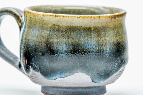 Close-up of a single cup, showing the blue-green drip glaze and side handle.
