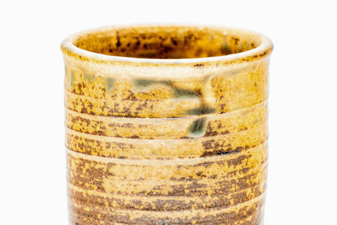 Close-up of a cup, showing the brown-and-yellow drip glaze.