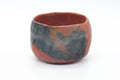 Handbuilt Aka-raku matcha chawan with a mottled red-and-grey glaze and organic incurved form, front view.