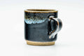 Three-quarter view emphasising the handle and the pale drip glaze breaking over the rim.