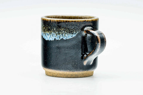 Three-quarter view emphasising the handle and the pale drip glaze breaking over the rim.