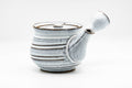 Milky-white glazed kyusu teapot at a three-quarter front angle, ribbed spiraling bands around the body with a side handle on the right and a brown-edged rim.