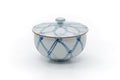 The lidded cup at a slight angle, showing the blue geometric design.