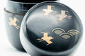 Overhead close-up of the matcha caddy lid showing the gold geometric soaring-bird and wave maki-e pattern
