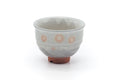 Front view of a grey-white Hagi-yaki yunomi with pink gohonte spots and an exposed clay foot.