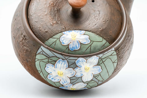 Three-quarter view highlighting the painted white lily panel on the textured body.