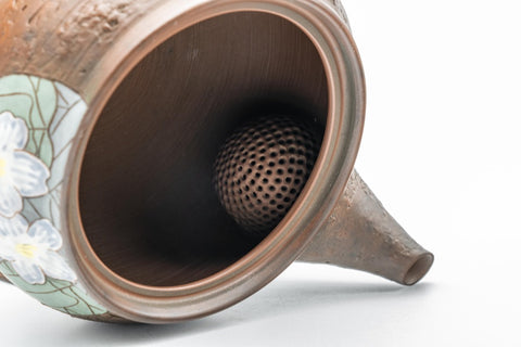 The teapot with its lid removed, revealing the dark interior and mesh strainer.