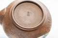 Close-up of the unglazed base showing throwing rings and the maker's mark.