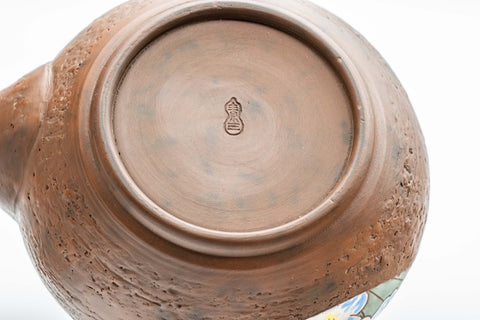 Close-up of the unglazed base showing throwing rings and the maker's mark.