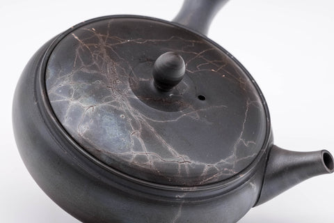 Mogake Seaweed Yōhen flat Tokoname teapot, three-quarter view showing the reddish seaweed mogake markings across the dark body, spout to the right