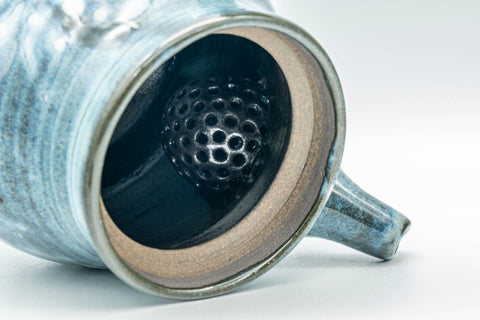Overhead view with the lid removed, revealing the dark glazed interior and mesh strainer.