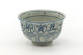 Three-quarter view showing rows of blue calligraphic characters around the rim.
