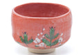 Three-quarter view emphasising the painted floral motif on the red glaze.
